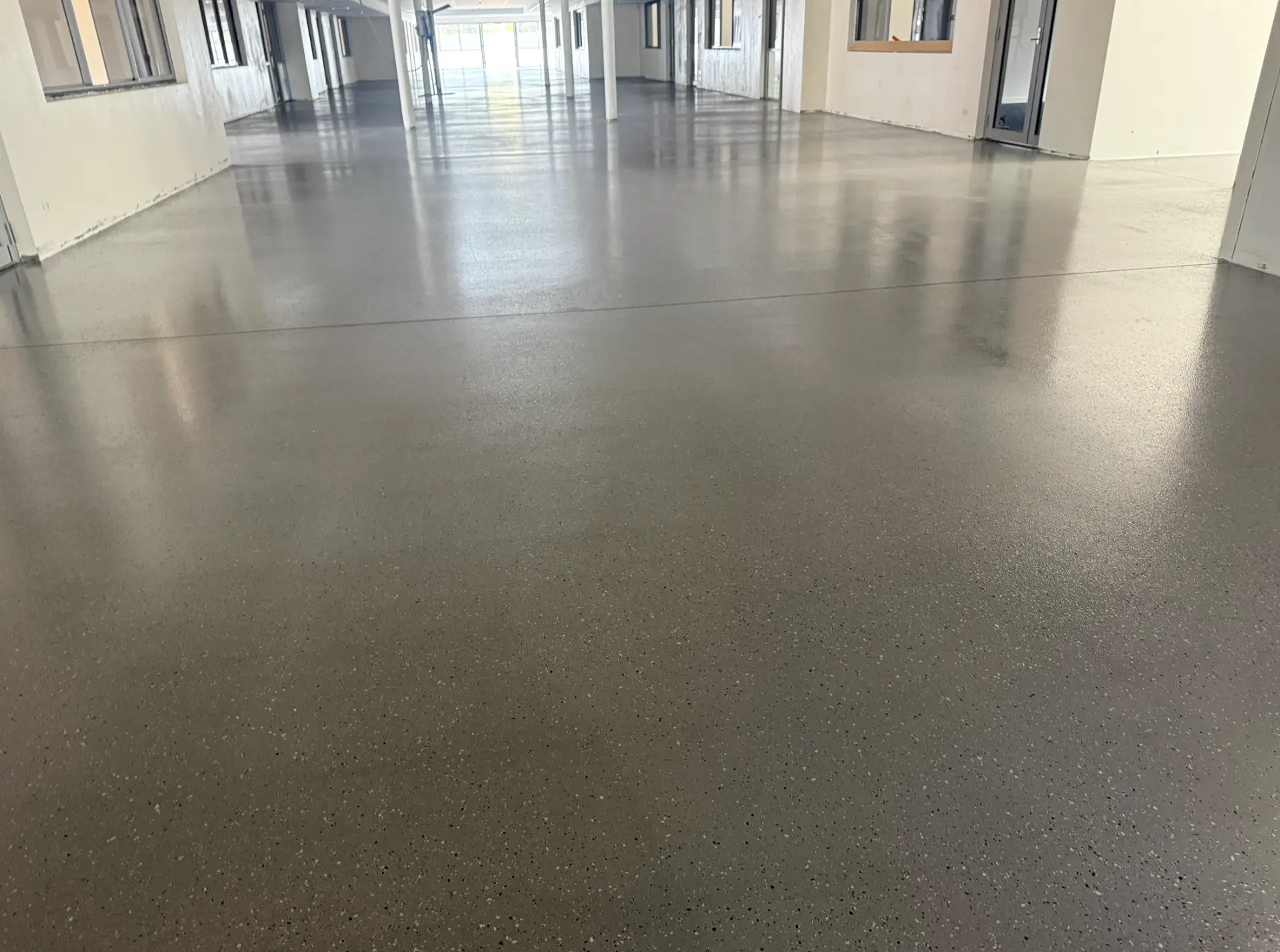 Wide grey epoxy floor running the length of a newly built commercial tenancy