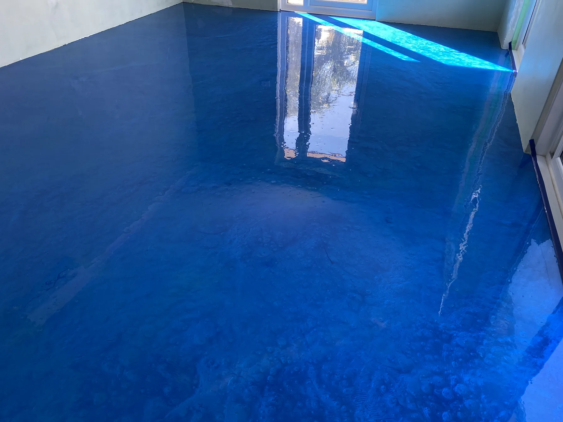 Charcoal and blue metallic epoxy floor with silver marbling in a covered alfresco area