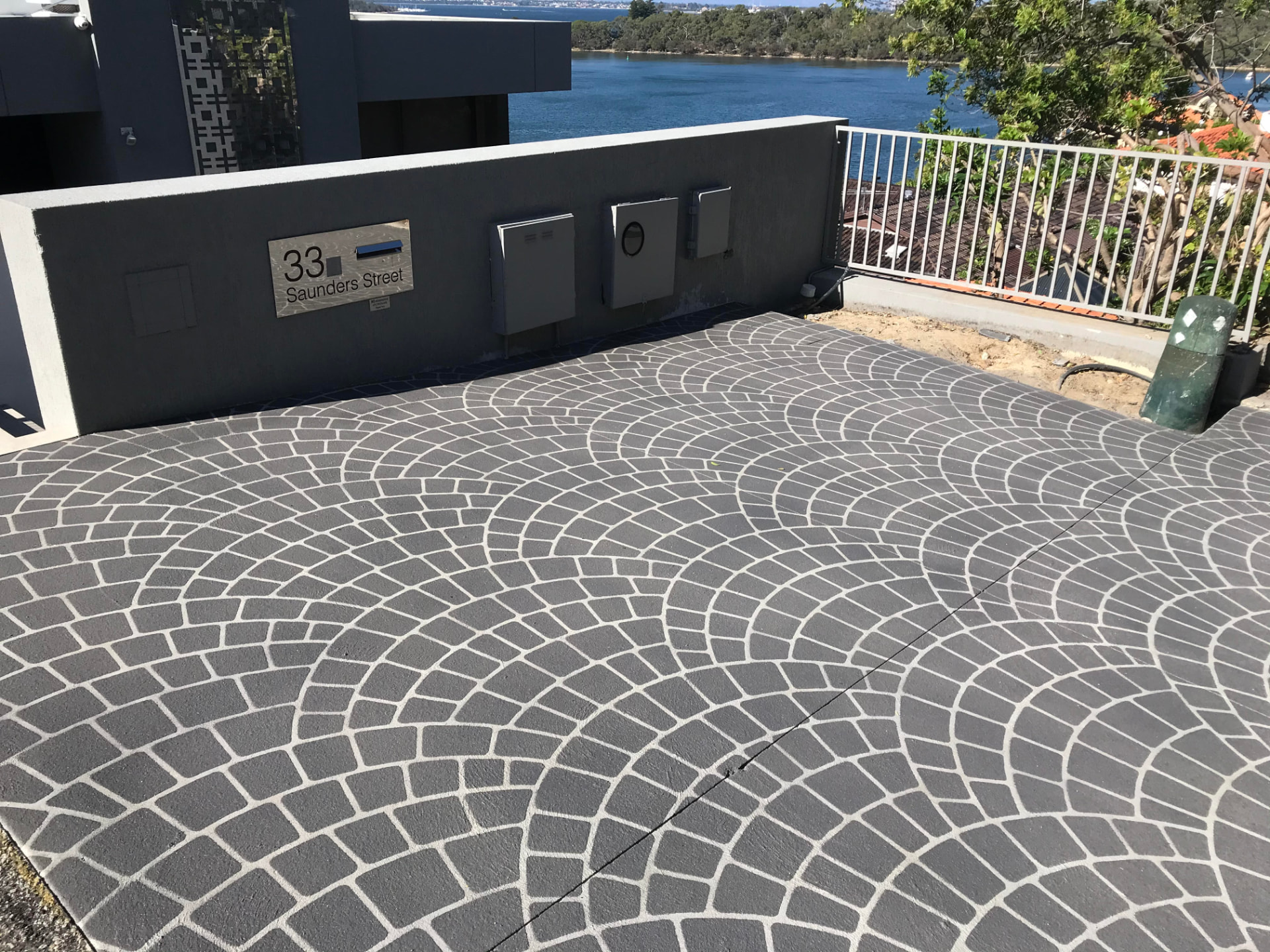 Finished slate grey European fan stencil spray-on concrete driveway with crisp white joint lines overlooking the river