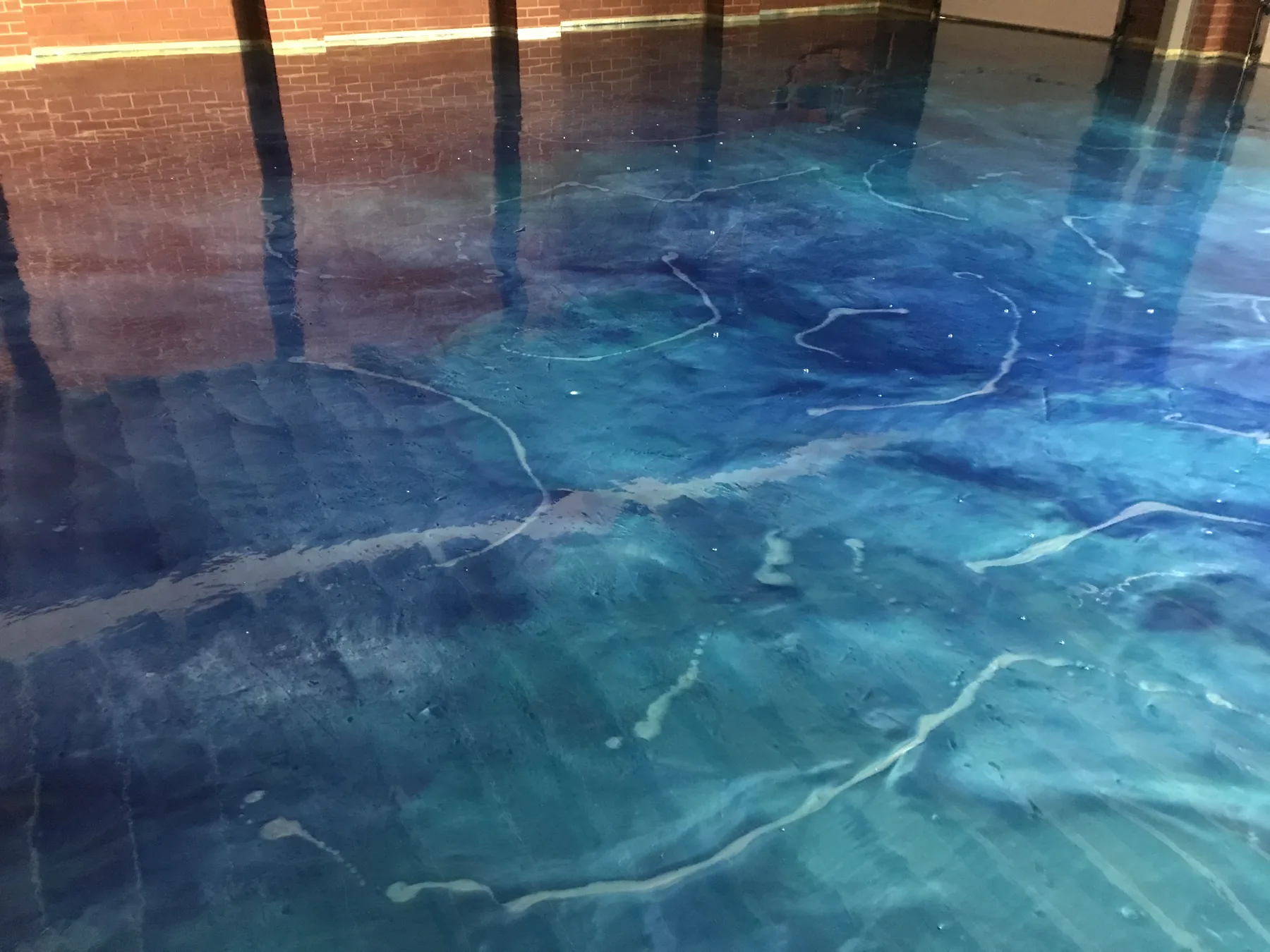 Teal and blue metallic epoxy floor showing marbled pigment flow under a gloss finish