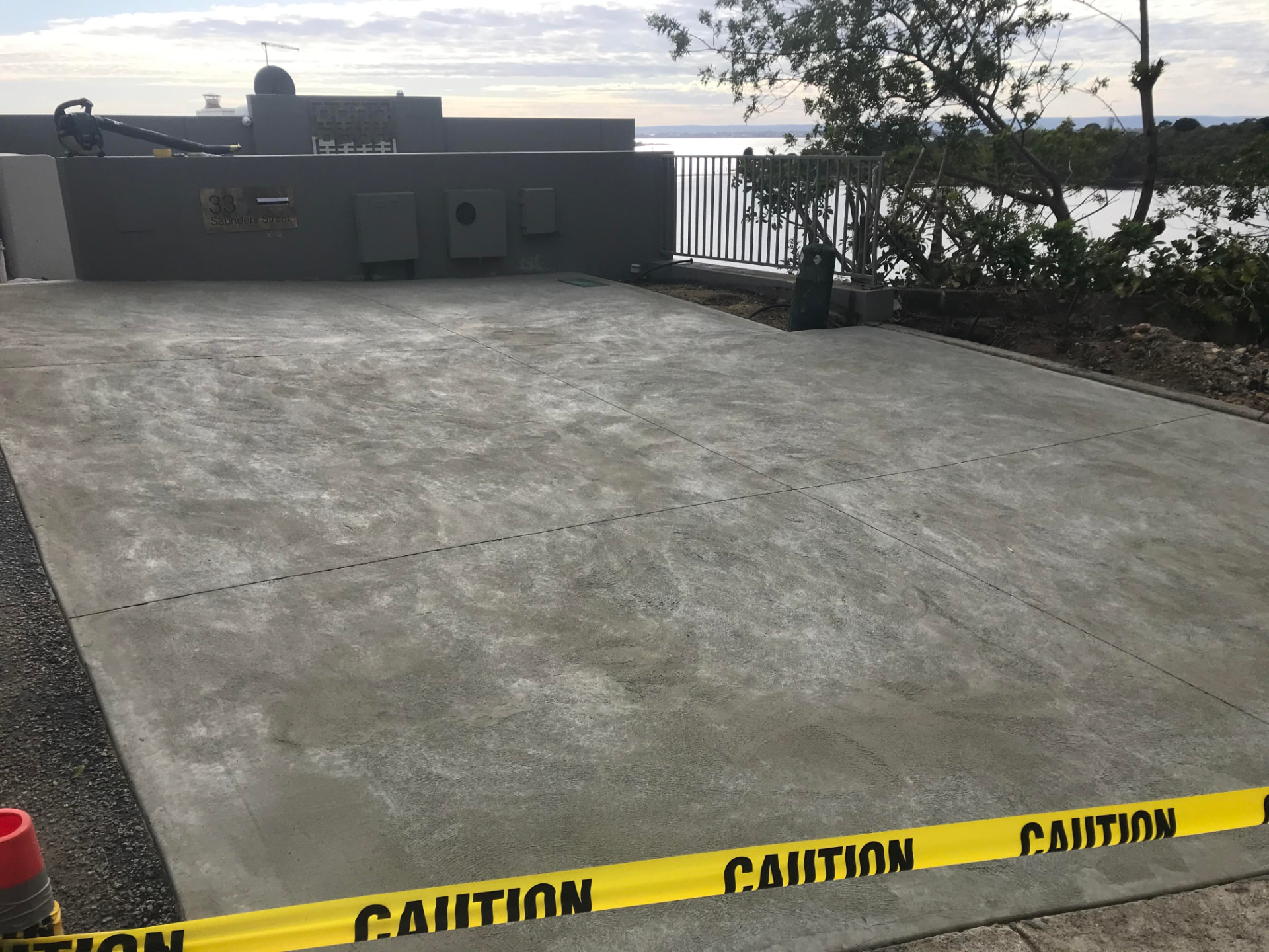 Plain grey riverfront driveway with patchy tired concrete before European fan stencil spray-on resurfacing in Perth
