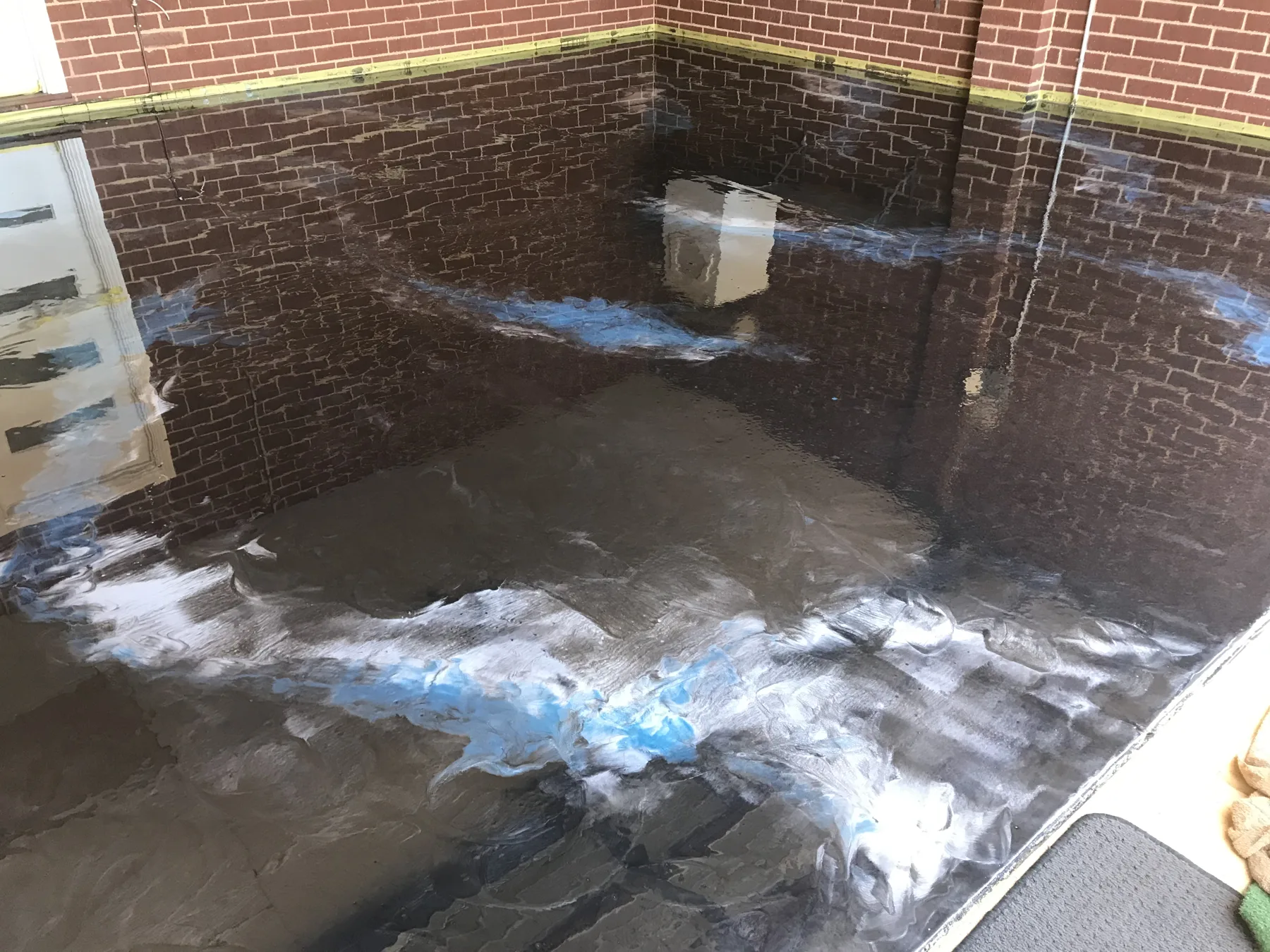 Metallic epoxy floor in progress with blue and white pigment worked through the resin