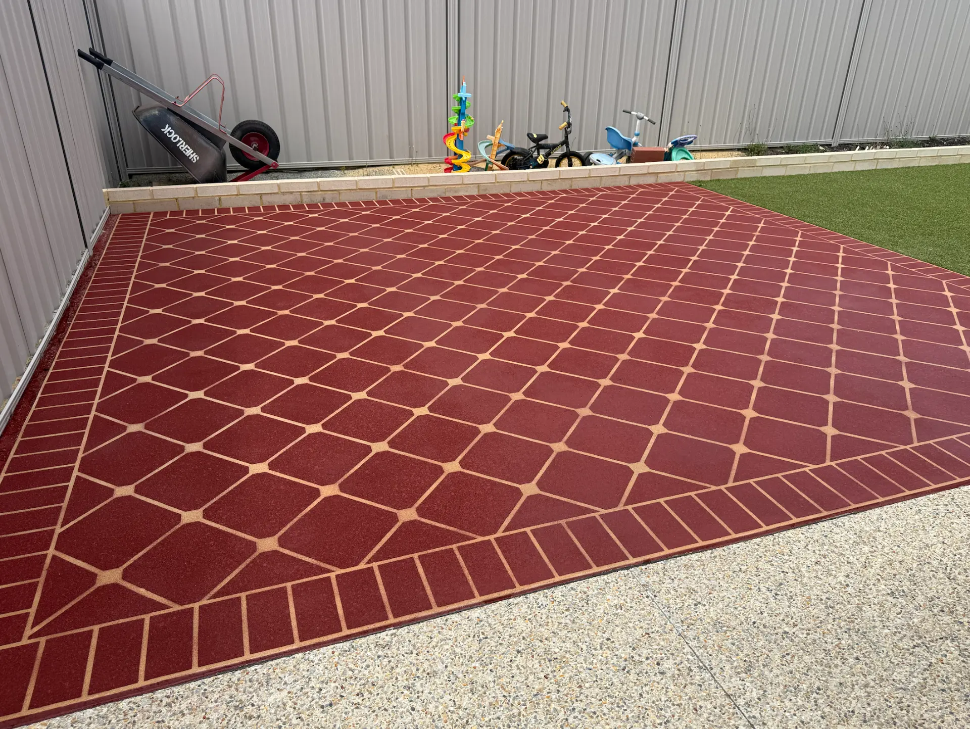 Terracotta diamond-pattern stencil spray-on concrete patio with a faux-brick border and exposed aggregate surround at a Perth home
