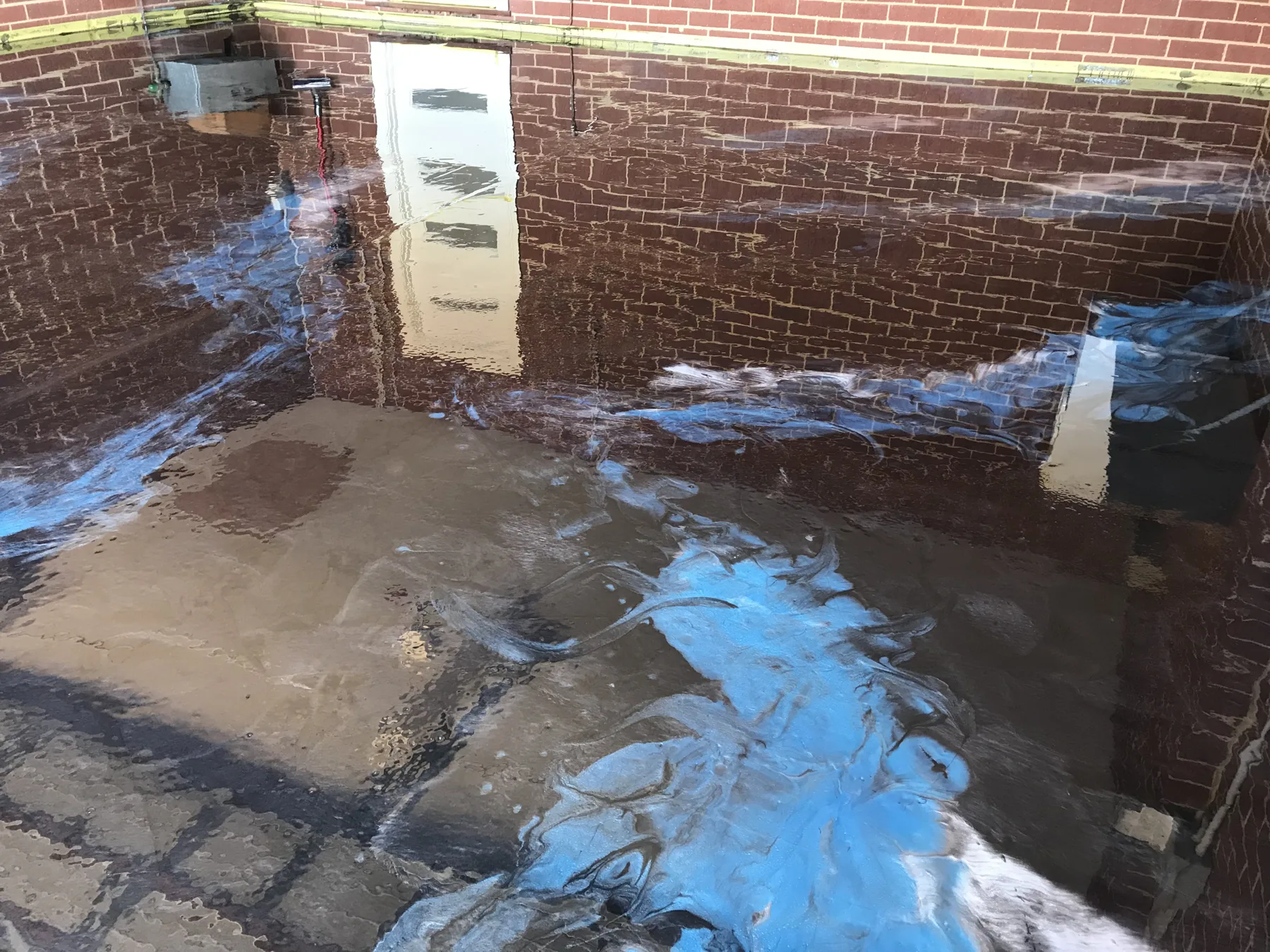 Deep blue metallic epoxy floor with light veining reflecting a brick wall