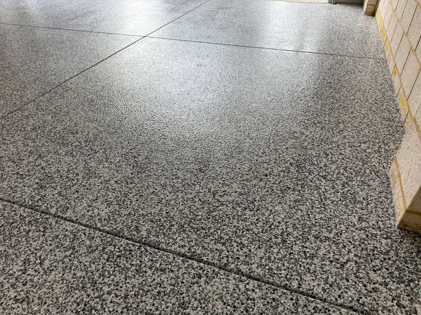 Grey and white flake floor coating with a speckled aggregate-look finish and cut joint line